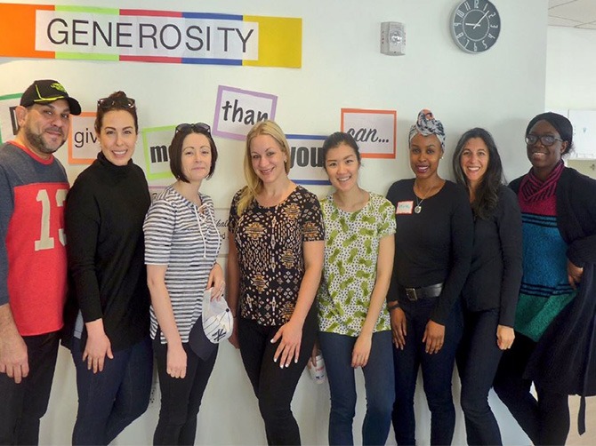 A group of people standing in front of a wall that says generosity.