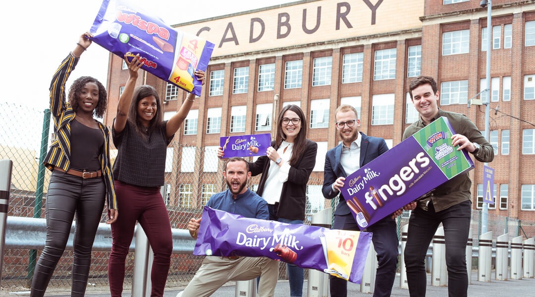 Group of people holding large candy in front of the Cadbury factory