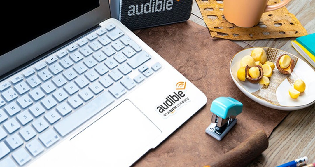 Laptop on a desk showing the keyboard and the Audible logo.