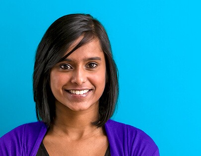 A woman smiling in front of a blue background.
